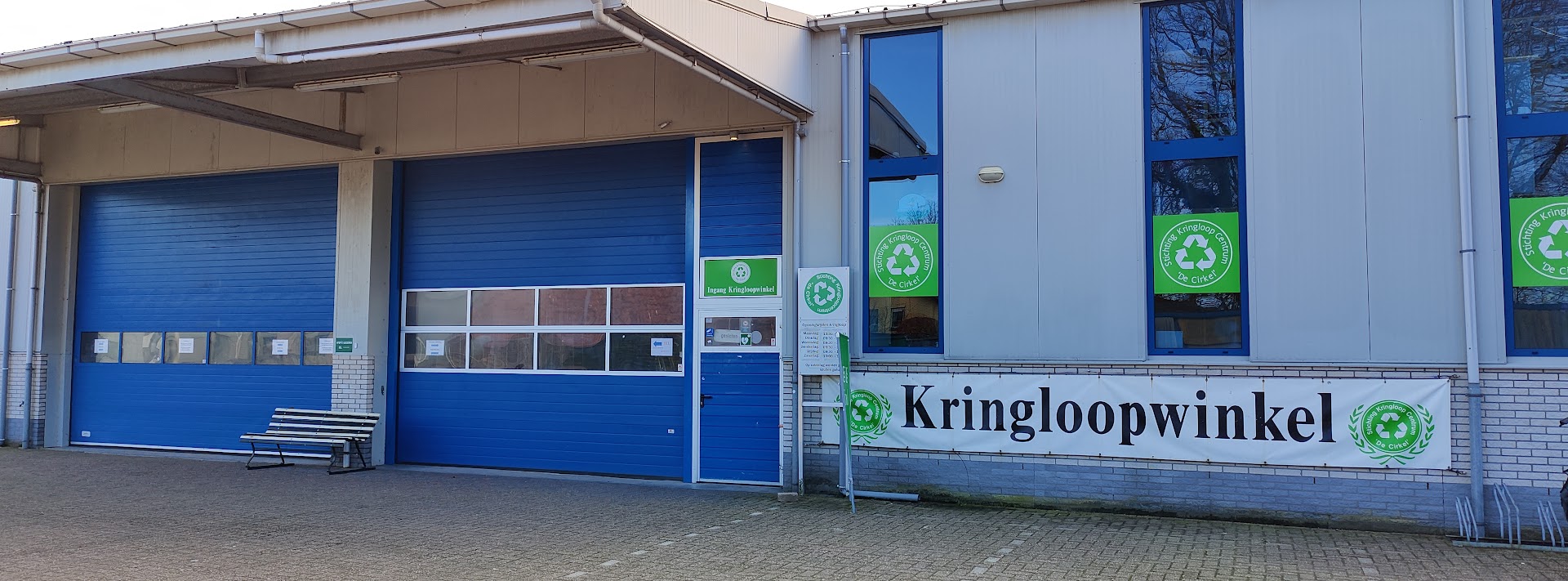 Ingang van de kringloopwinkel met blauwe overheaddeur